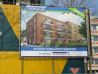 833391 Afbeelding van een reclamedoek voor het nieuwbouwproject 'Tuinwijk' (42 koop-zorgappartementen), op de hoek van ...